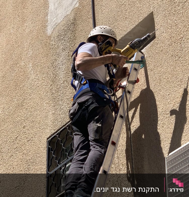 אדם על סולם עם מקדחה ליד פתח קיר